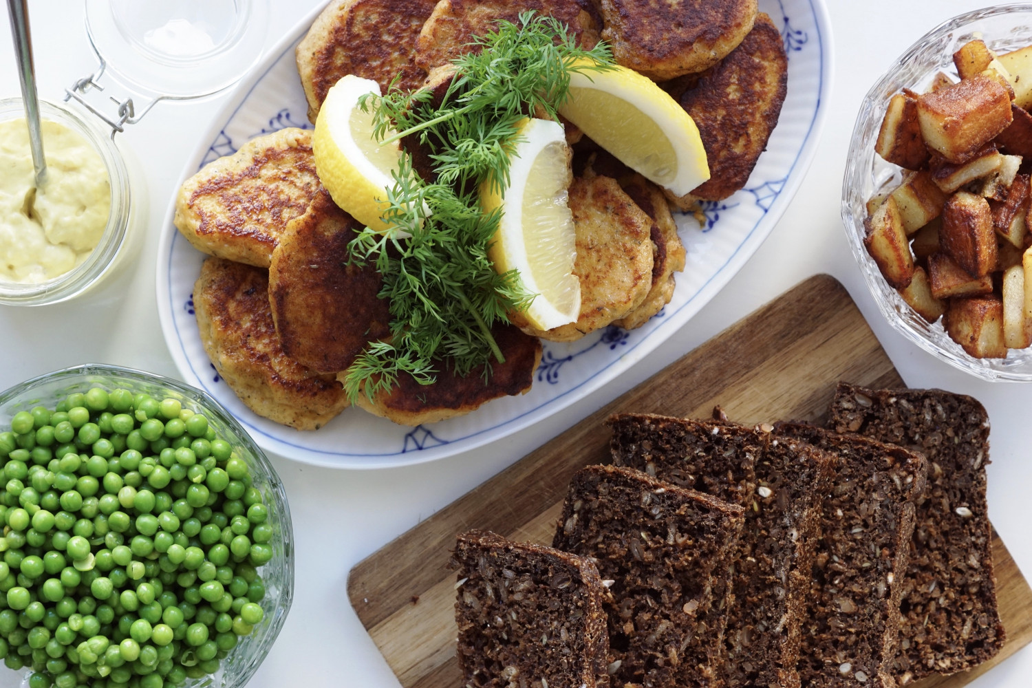 Laksefrikadeller med brasede kartofler, ærter og remoulade